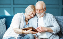 mature age adult couple smiling and sitting together on couch enjoying retirement